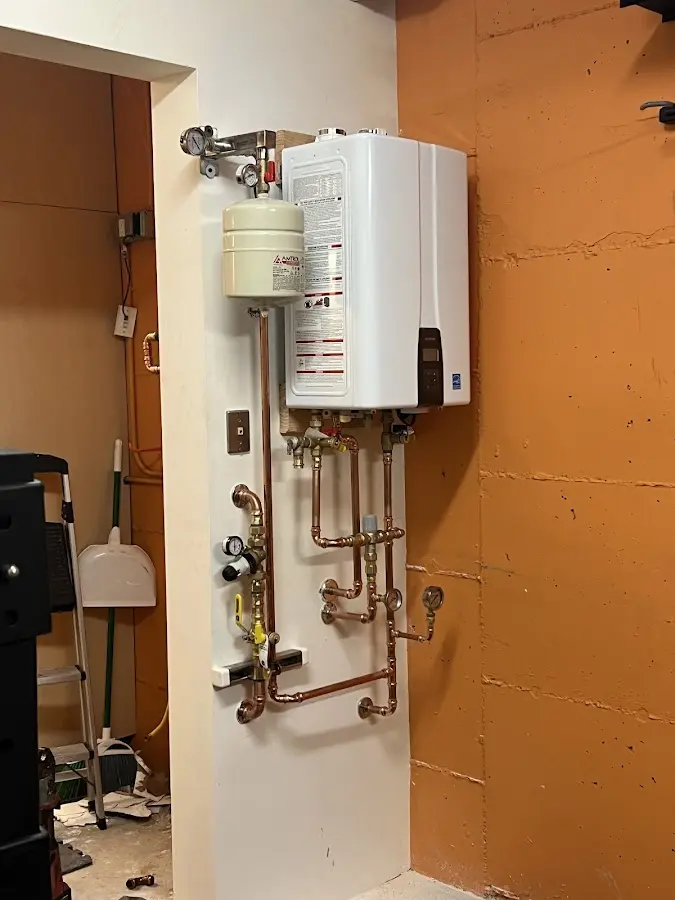 Plumbing technician inspecting water heater connections in East End